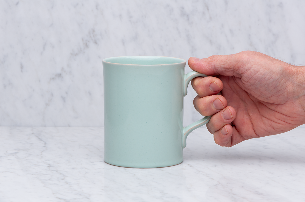 Ljusgrön temugg i keramik med hand som håller i handtaget. 5 dl