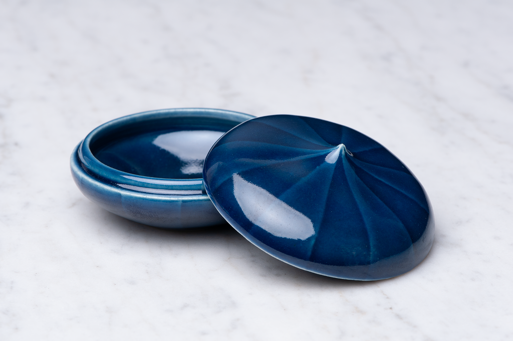 Mörkblårandig keramikask med locket på sidan